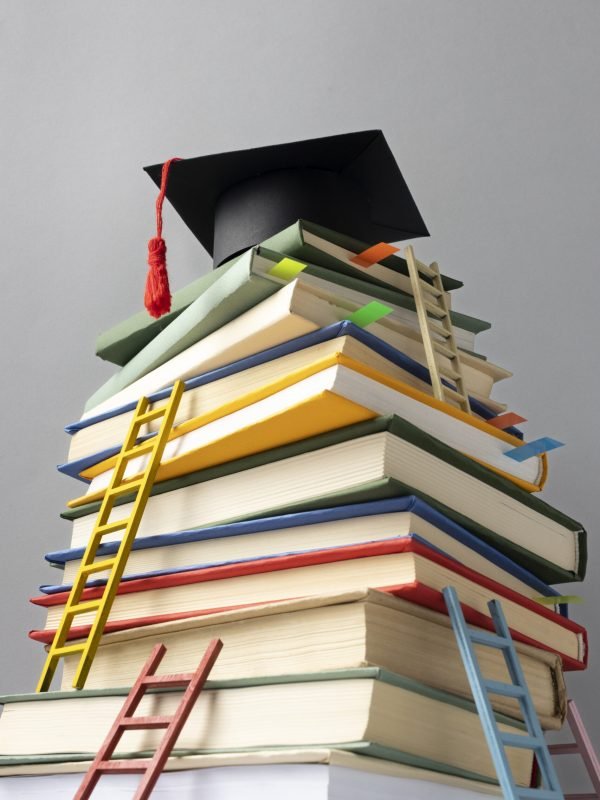 low-angle-stacked-books-graduation-cap-ladders-education-day